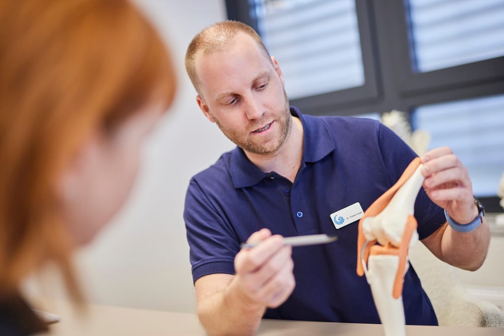 Dr. Vogel erläutert einer Patientin Aufbau und Funktion des Kniegelenks am Anatomie-Modell