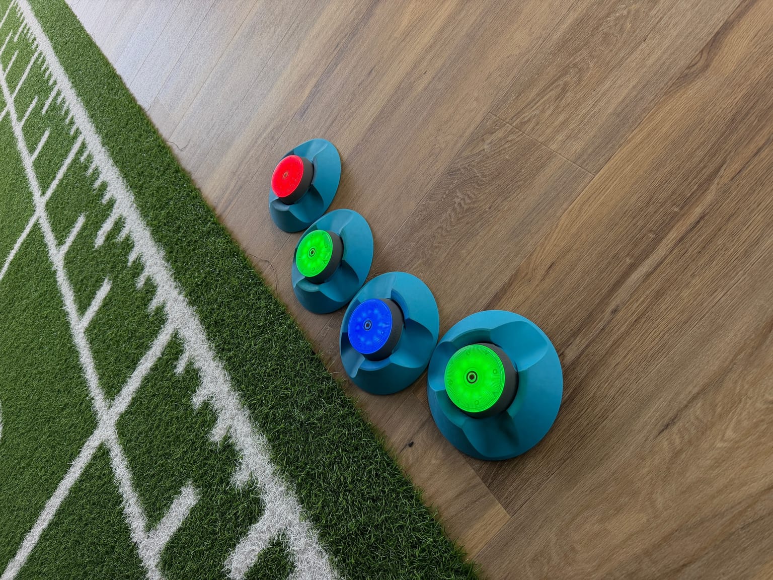 Vier leuchtende Blazepods in Rot, Grün und Blau auf dem Boden im Trainingsraum von Ortho4Sport Köln — Equipment für Reaktionstraining in der Trainingstherapie